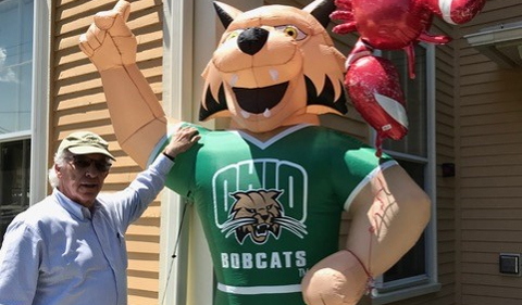 Alan Rom standing with a blow-up Rufus the Bobcat