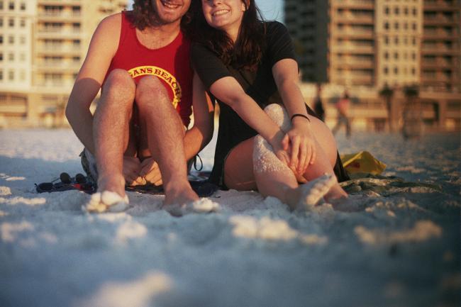 Photo of two figures sitting on a beach