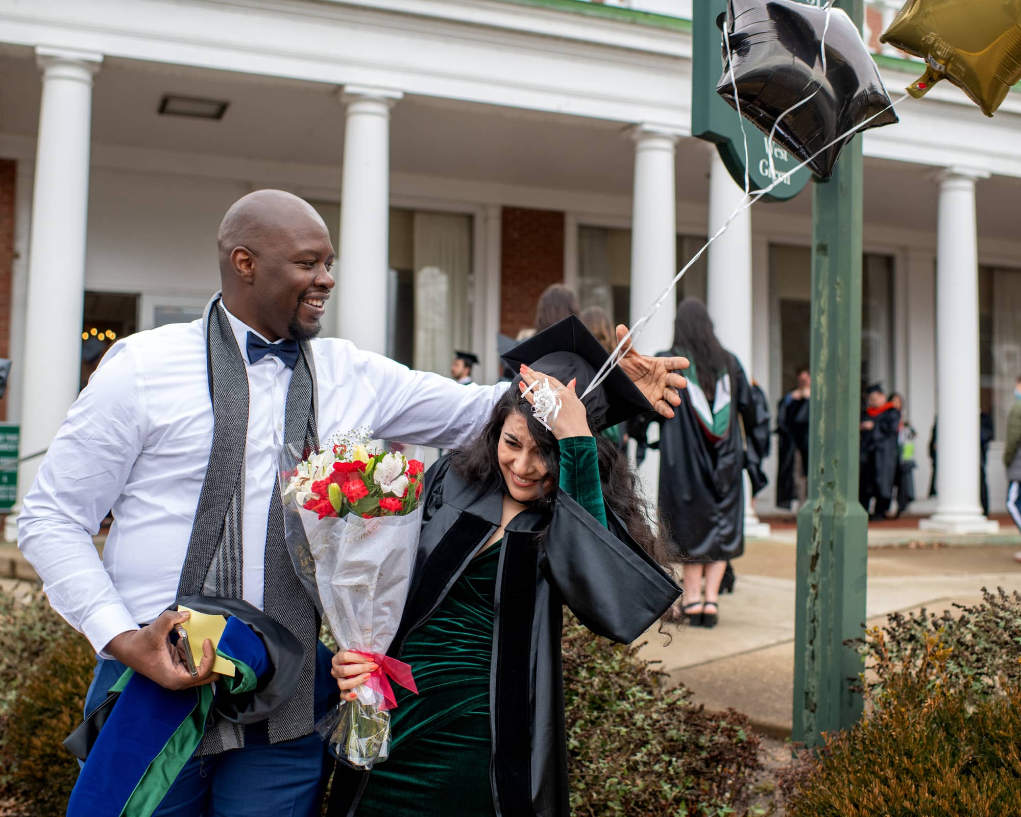 Two friends share a light moment prior to the Fall Commencement 2021 at the Athens Campus.