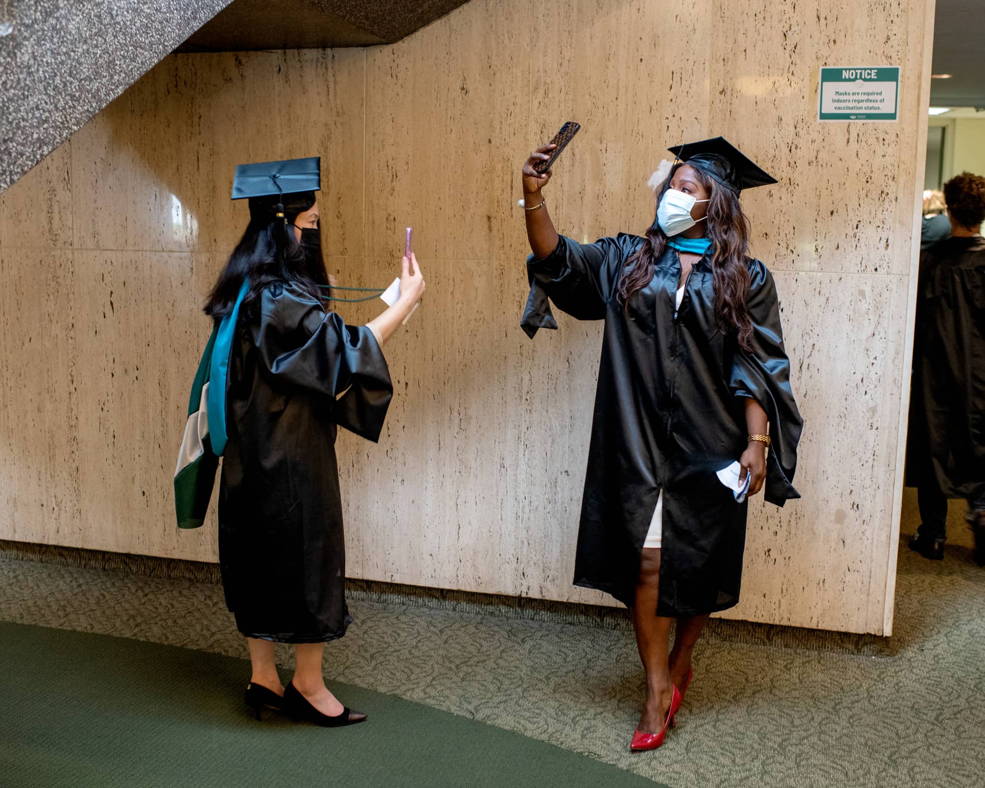 Two students anticipate the start of the Fall Commencement 2021 at the Athens Campus.