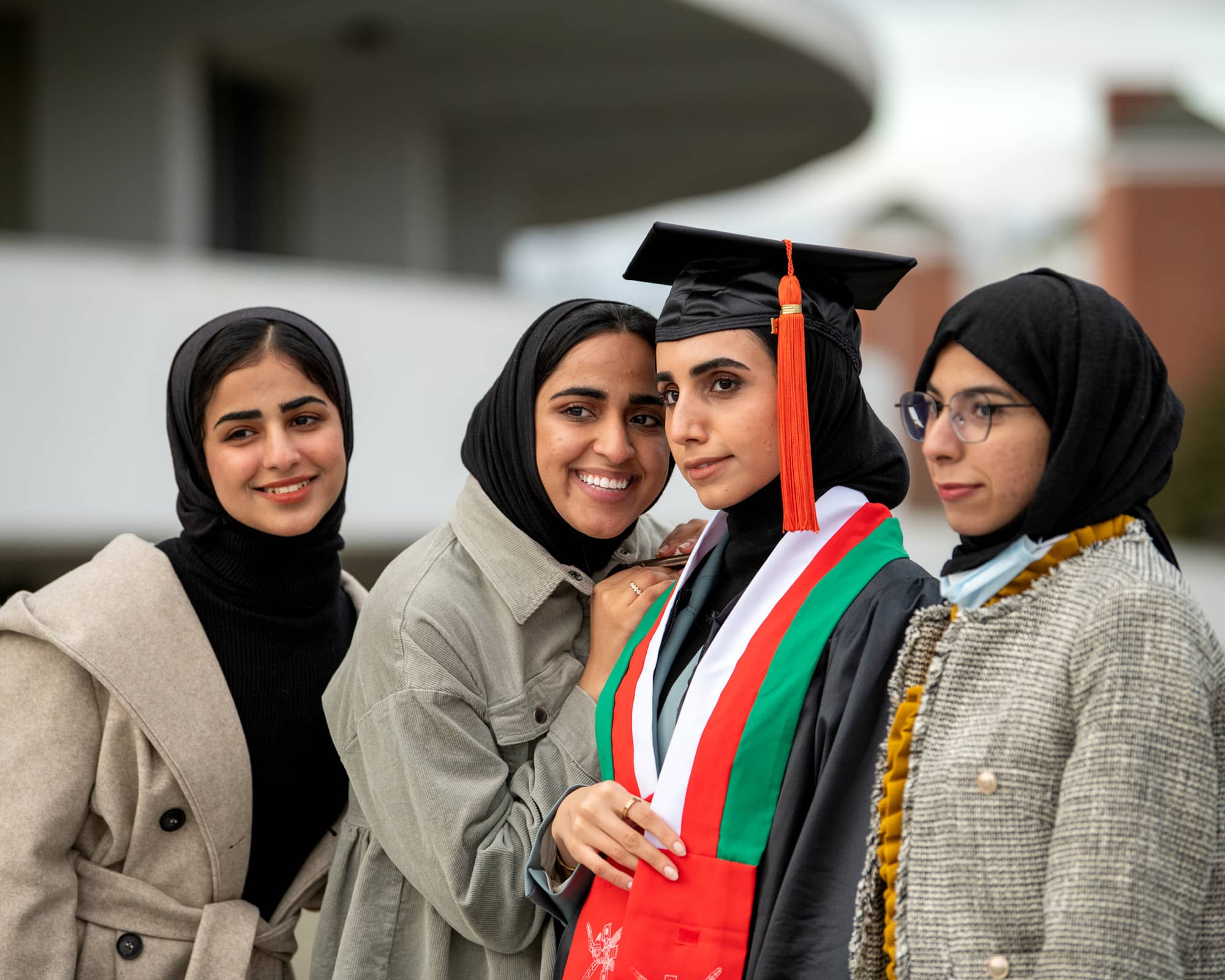 Recent graduate Shatha Mohammed Abdallah Al Balushi, center, has her photo taken by a friend after the Fall Commencement 2021 at the Athens Campus.