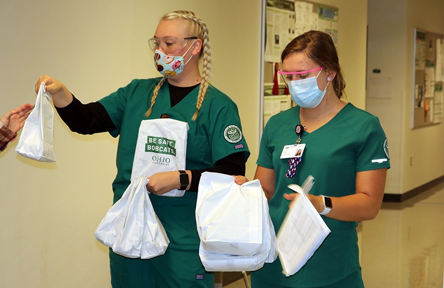 2 nurses with wearing PPE passing out Be Safe Bobcats bags