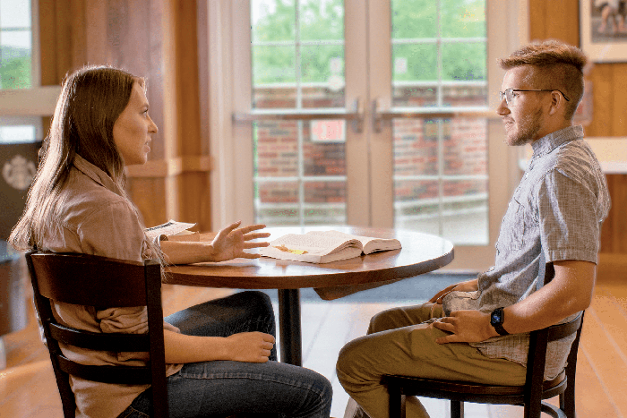 Two people talk at a table in The Front Room