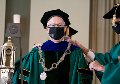 President Sherman is wearing a COVID-19 OHIO mask while being recognized. He is wearing a graduation gown and hat