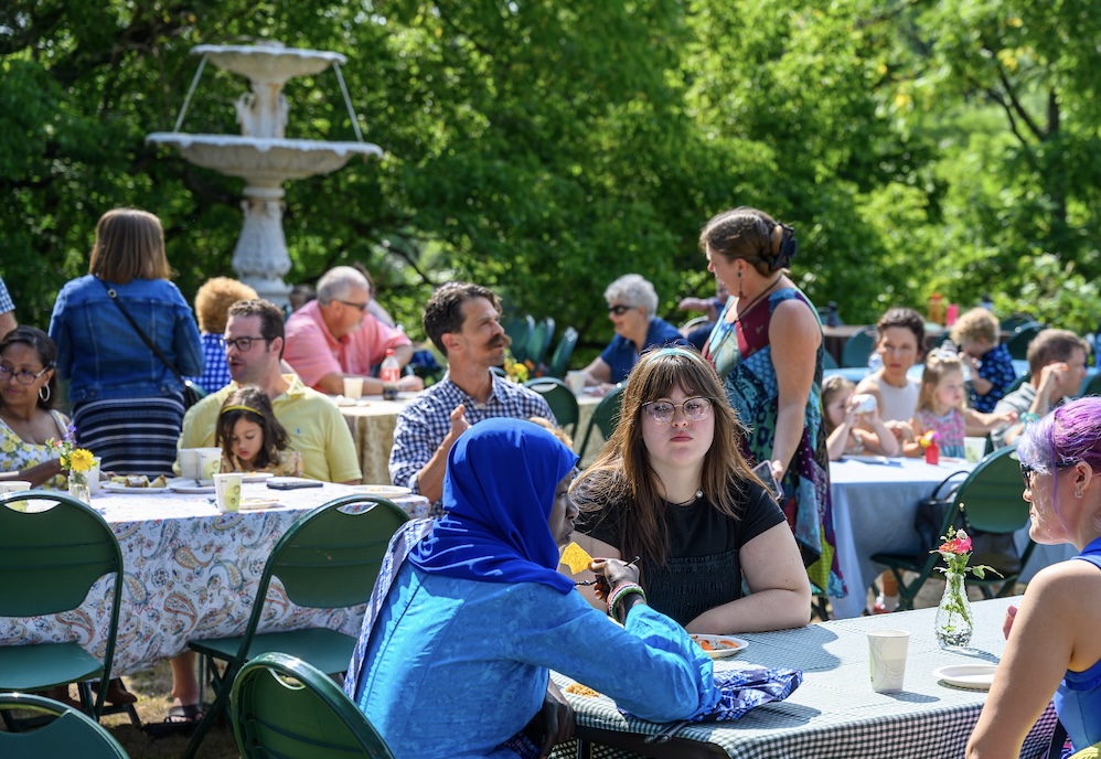 Groups of people sit at tables talking to one another