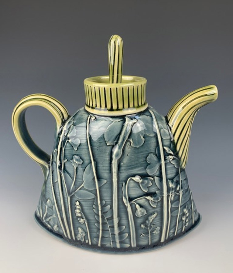 a blue and gold ceramic teapot on a gray gradient background