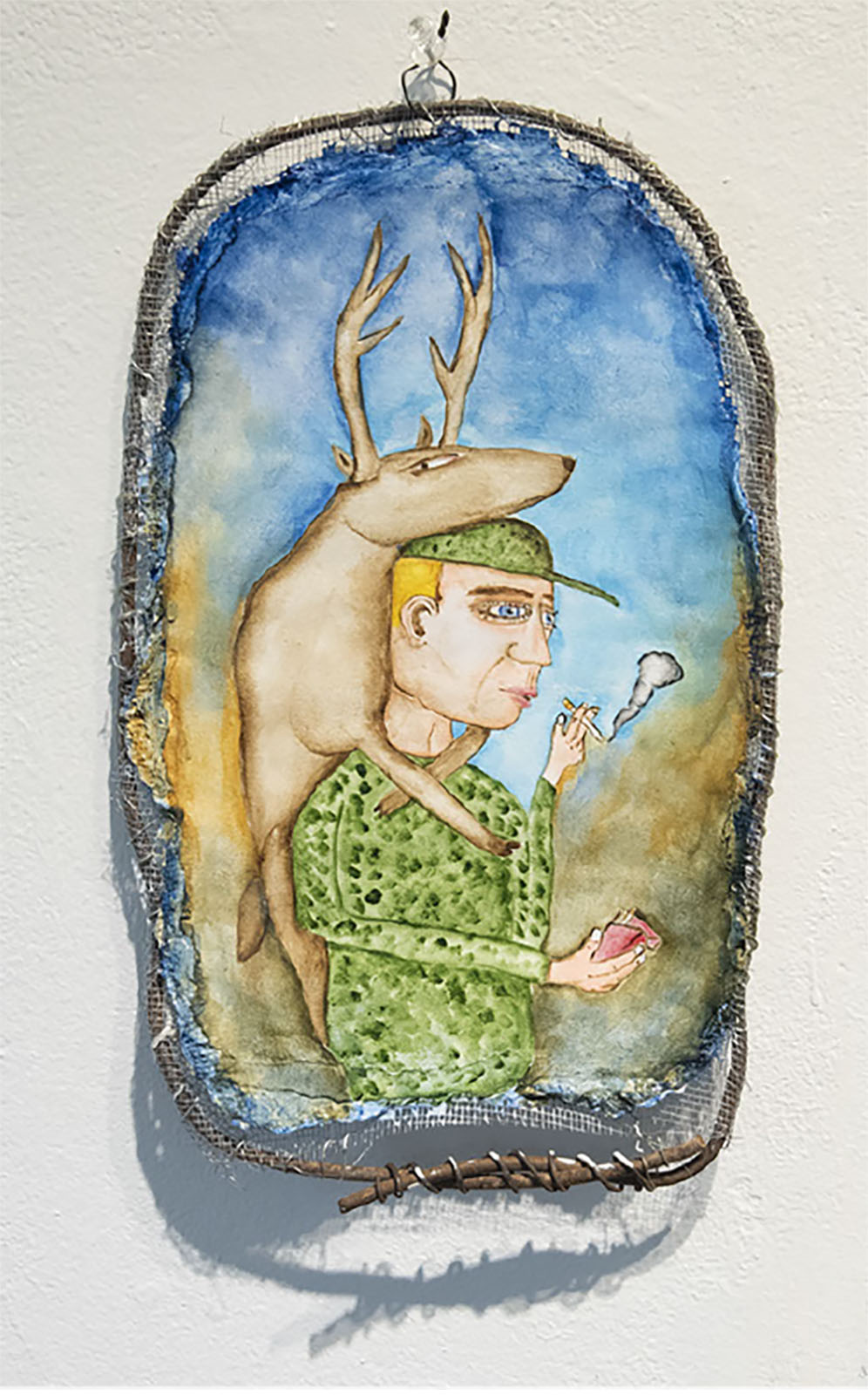 a colorful canvas depicting a white man with blond hair and camoflage-style shirt and hat carrying a deer with antlers on his back and smoking a cigarette