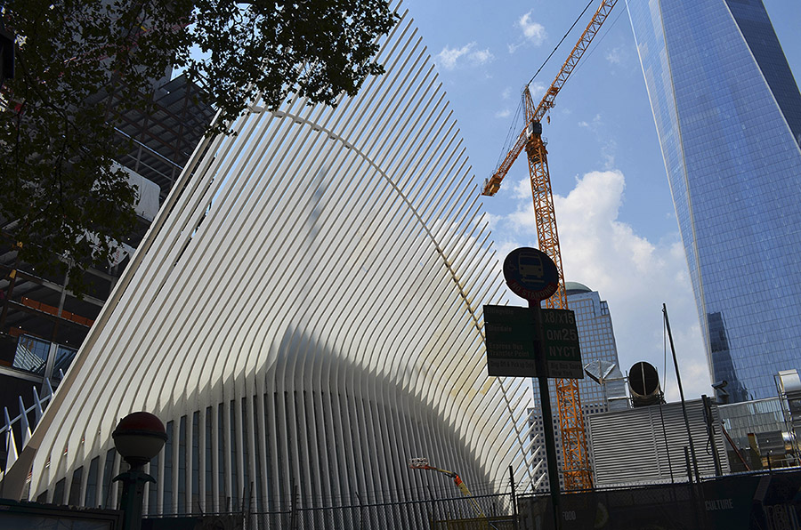 cityscape scene depicting several buildings and a large construction crane against a blue sky with fluffy white clouds