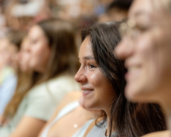 A student watches the new student convocation, smiling