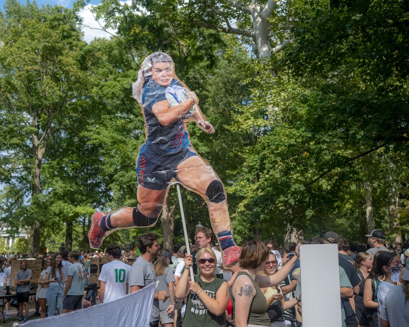 A smiling student holds up a life-size cutout of Olympic rugby player Ilona Maher