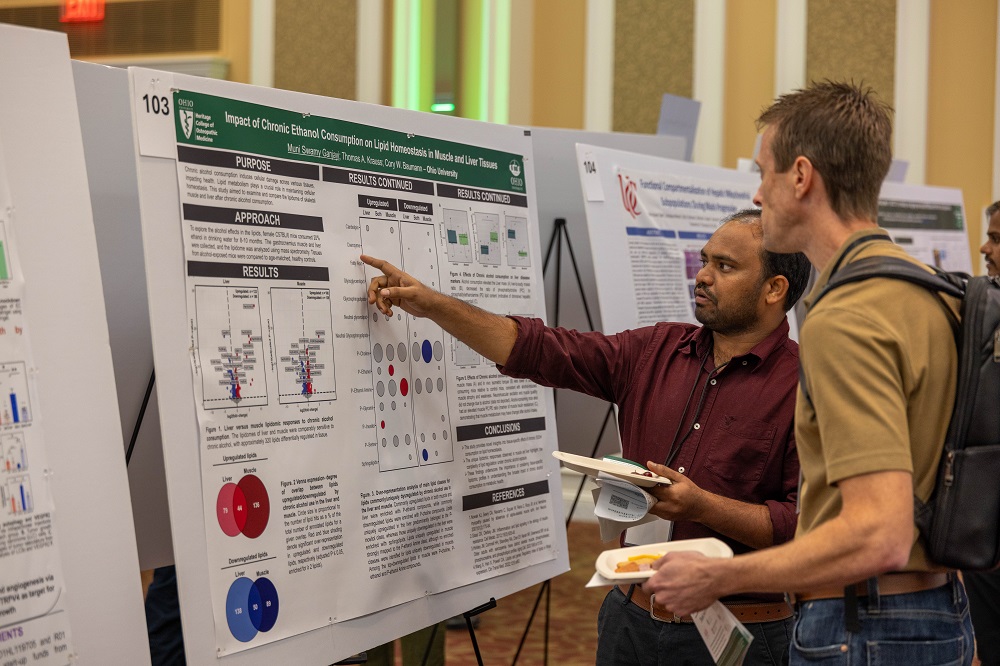 Two individuals look over a poster at the annual conference