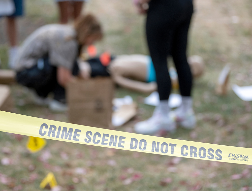 Students at Ohio University work on a mock crime scene behind yellow tape labeled 