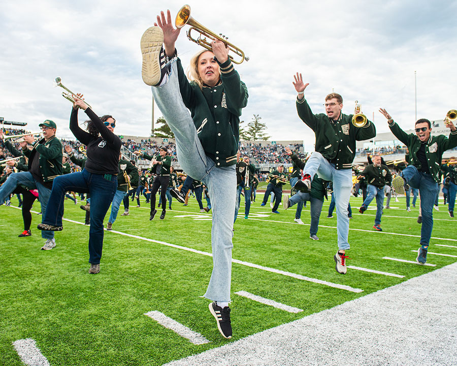 Brass players in the alumni marching band performing on the field