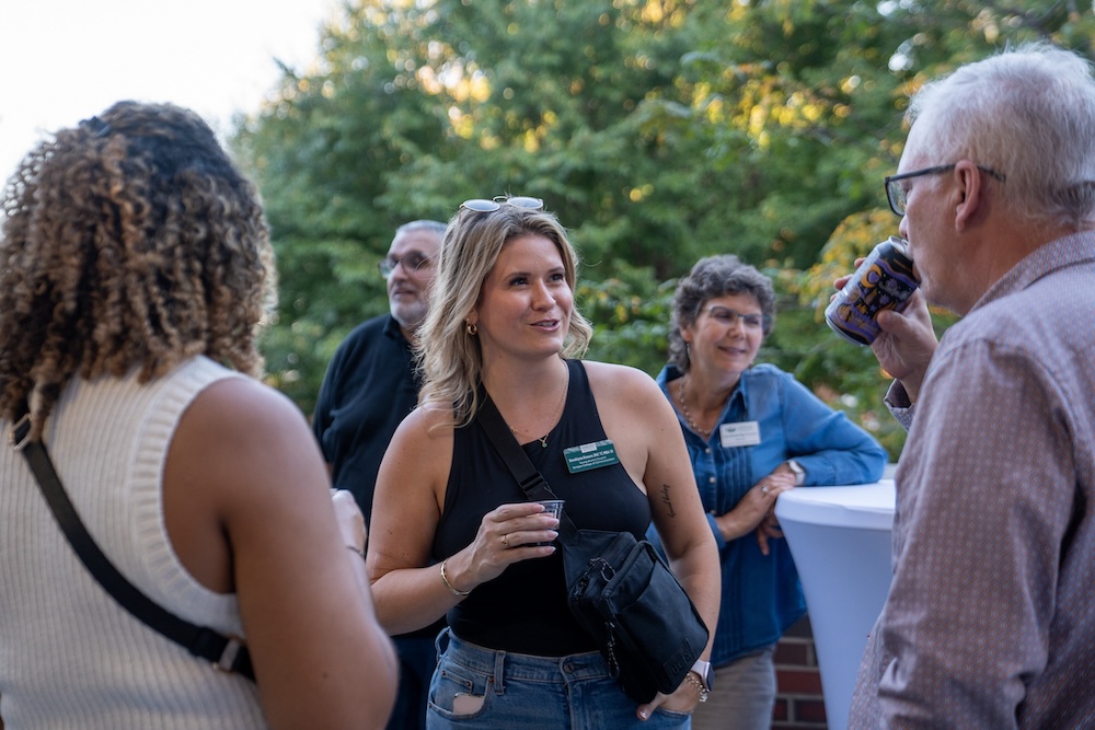 a group stands and talks holding drinks