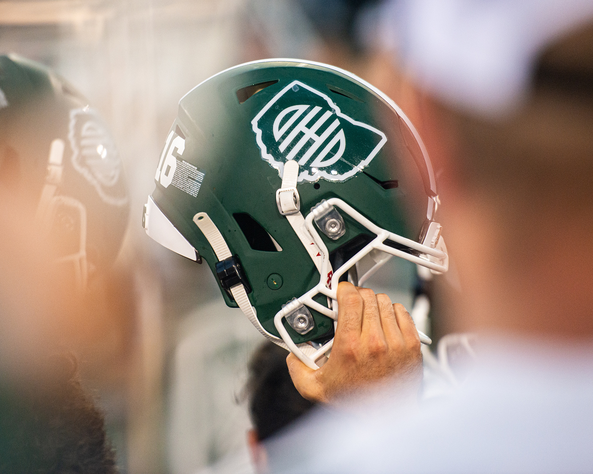 a hand grips a green Ohio University football helmet