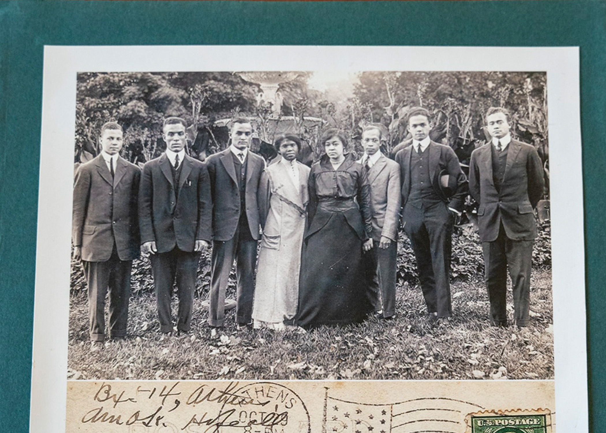 A black-and-white postcard of a group of people from the early 1900's