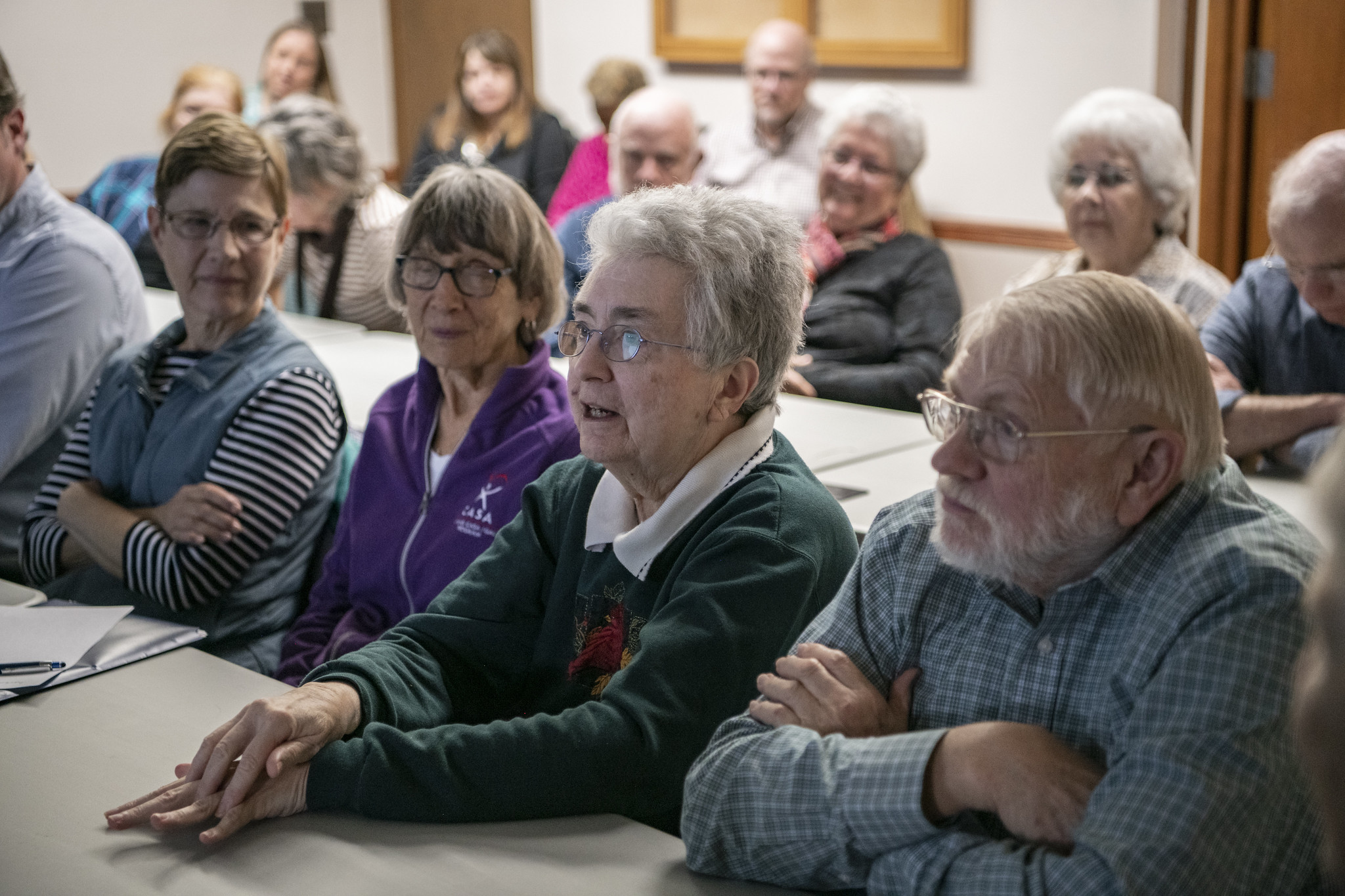 A group of older adults sits together in a meeting