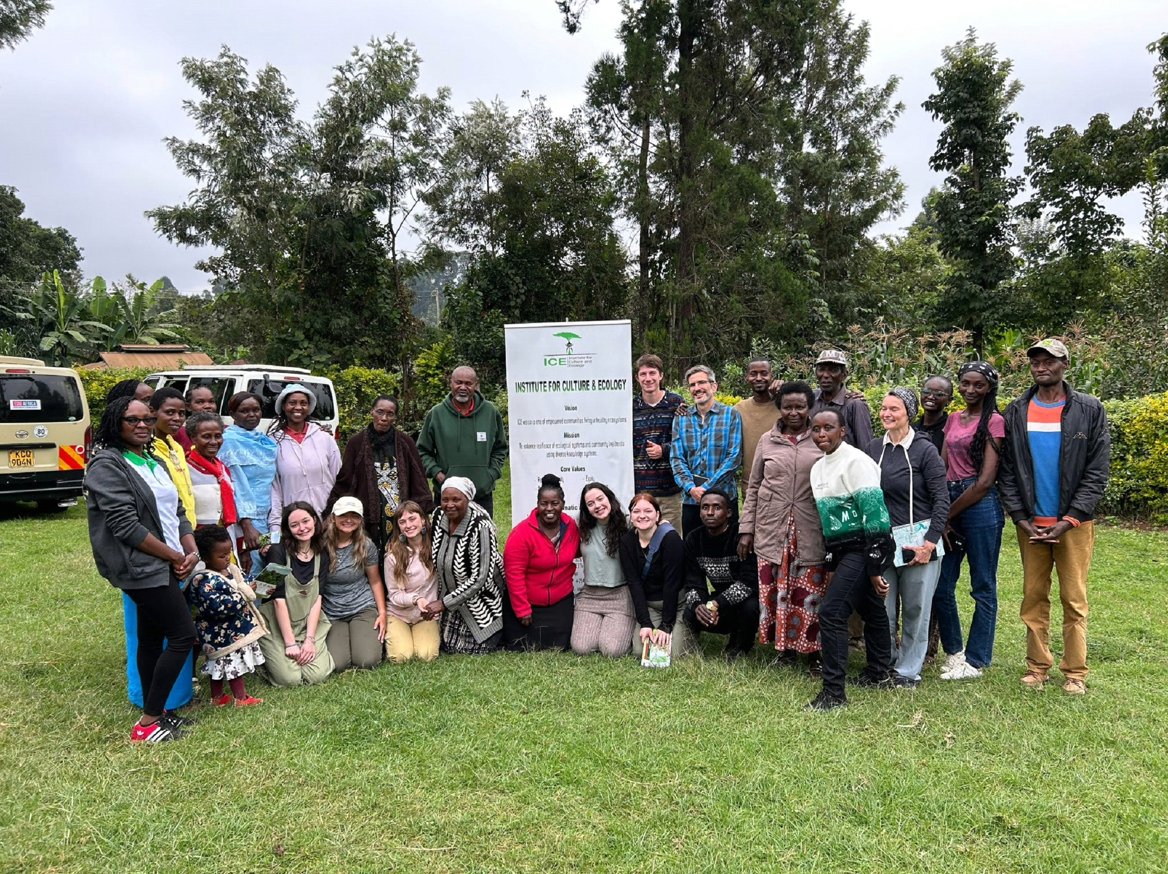 A group standing together in a forested area standing next to a sign that reads "Institue for Culture and Ecology."