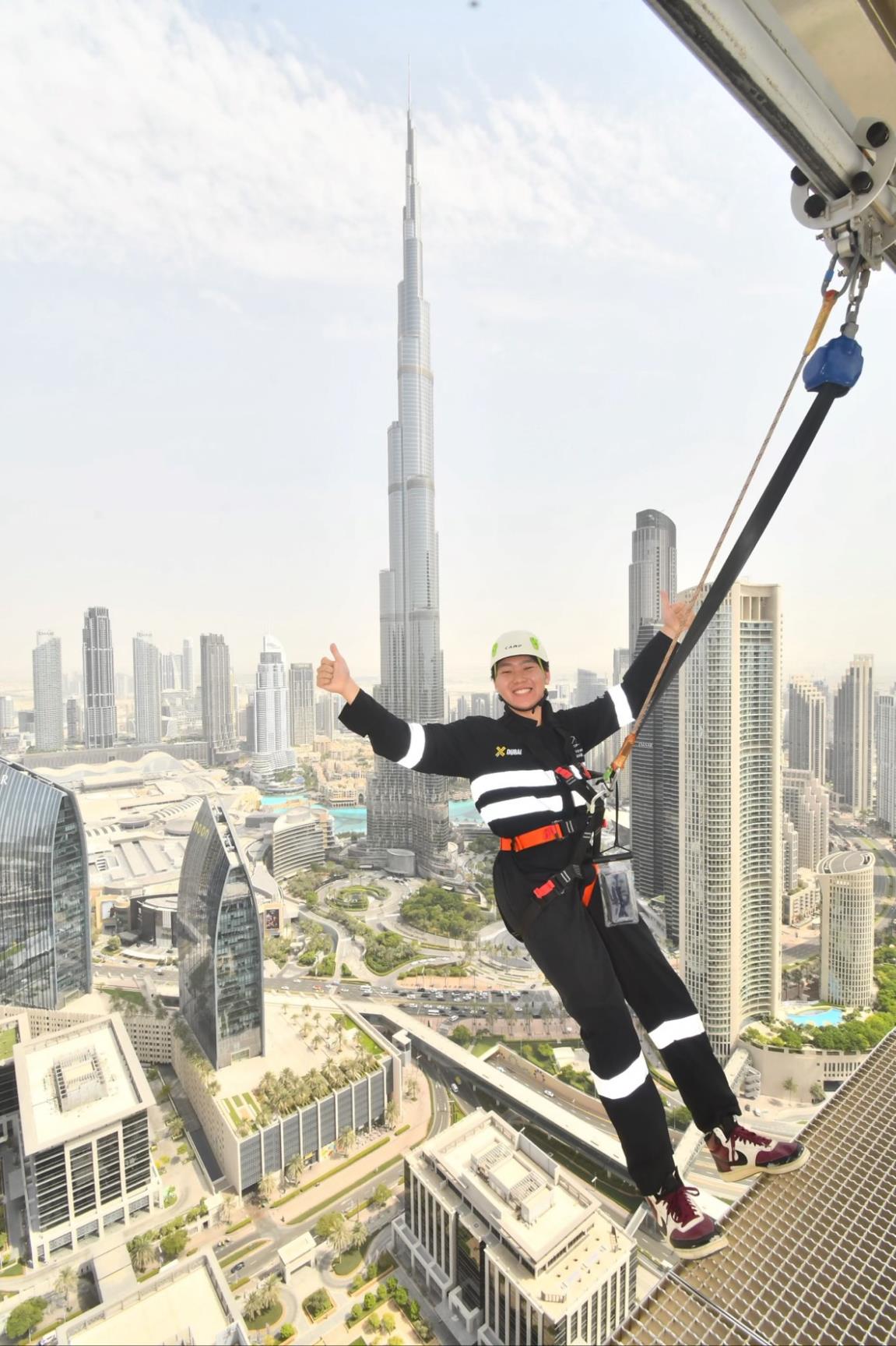 A man in a harness leans backwards over a cityscape