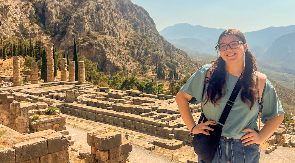 Student poses in front of ancient ruins in Greece