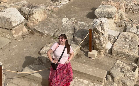 Student poses in front of ancient ruins in Greece