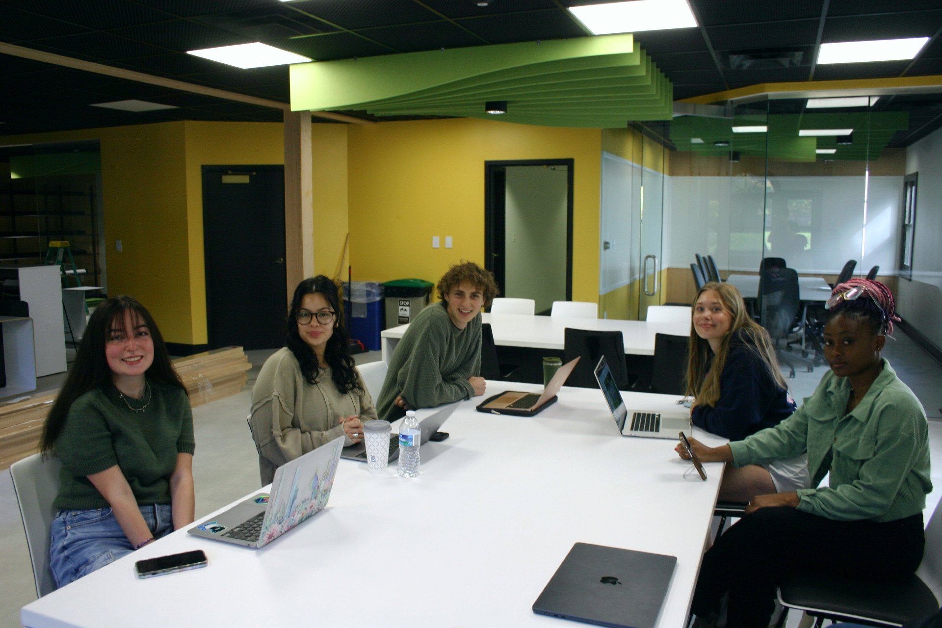 Students sitting at a conference table smiling. 