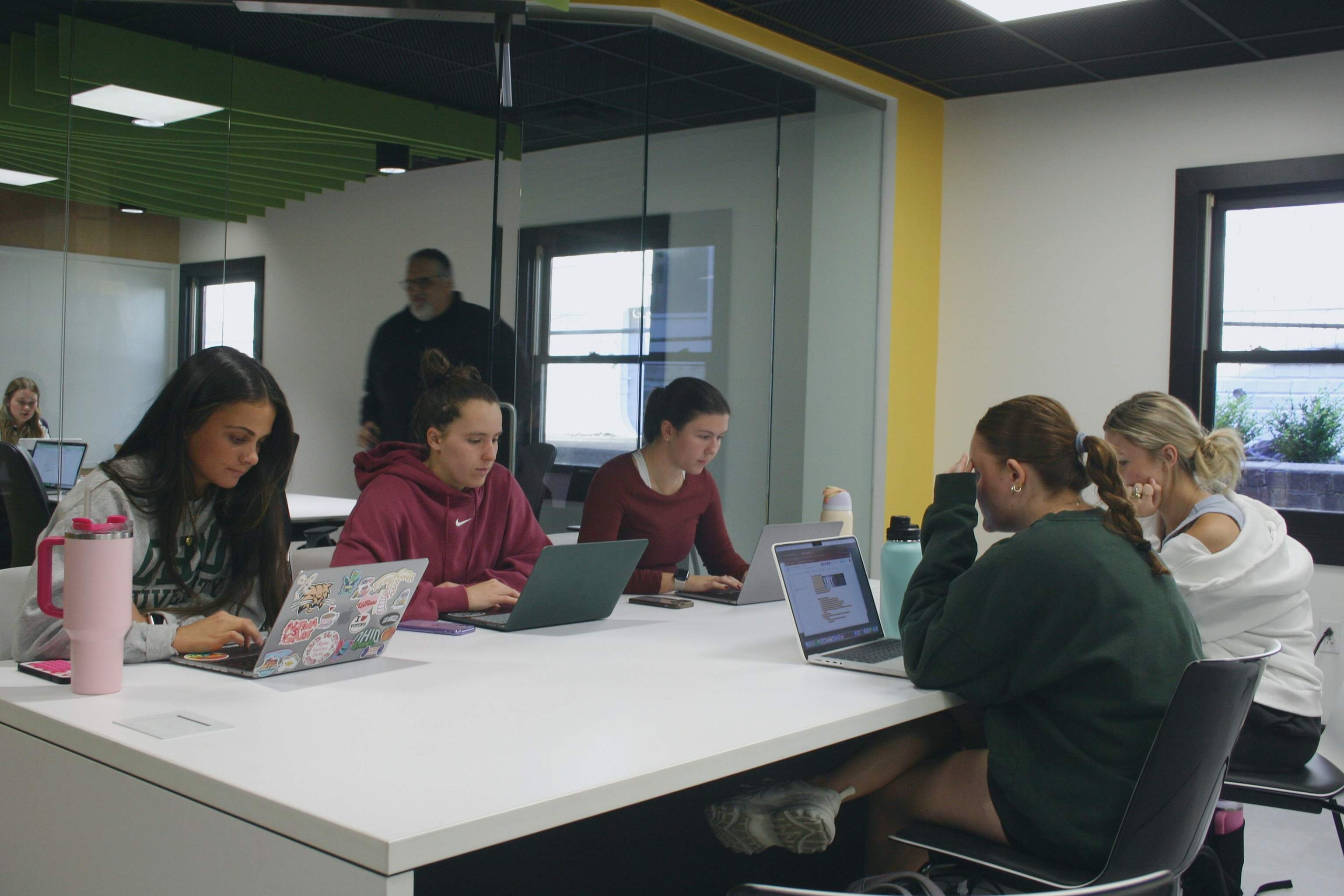 A group of students sitting at a desk in Sing Tao on their laptops.