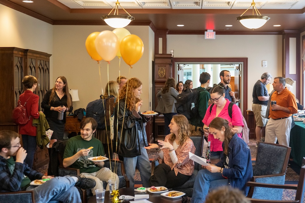 A reception room crowded with balloons and people eating and talking