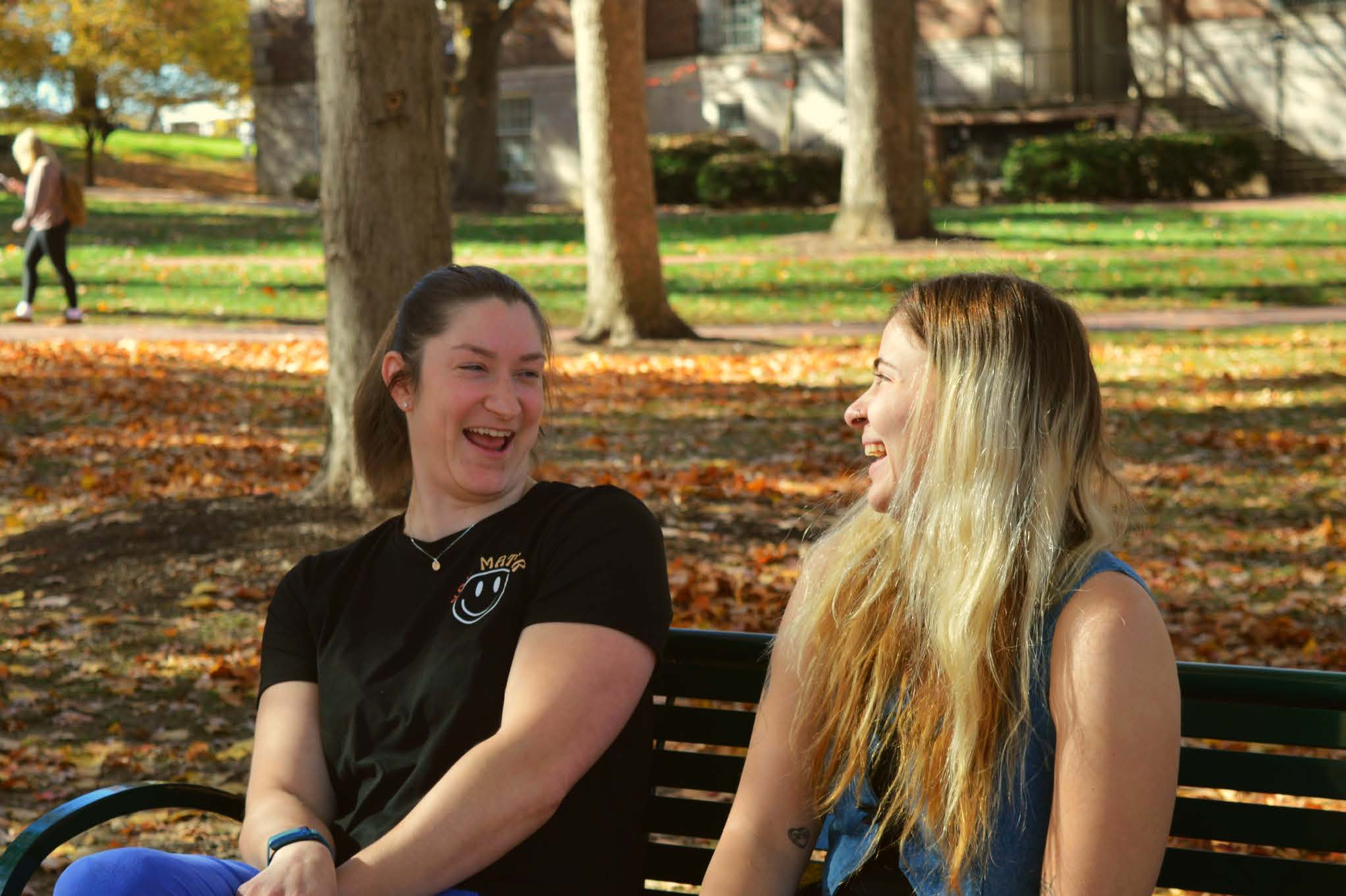 Laura Costa dos Santos and Sophia Hoffman laugh on a bench