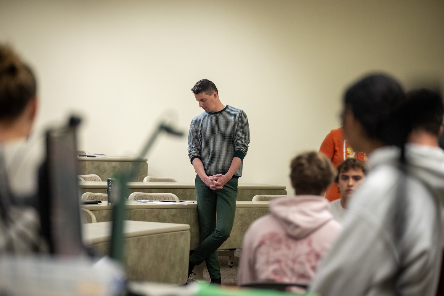 Chris Lewis stands in front of a classroom, looking down to his right