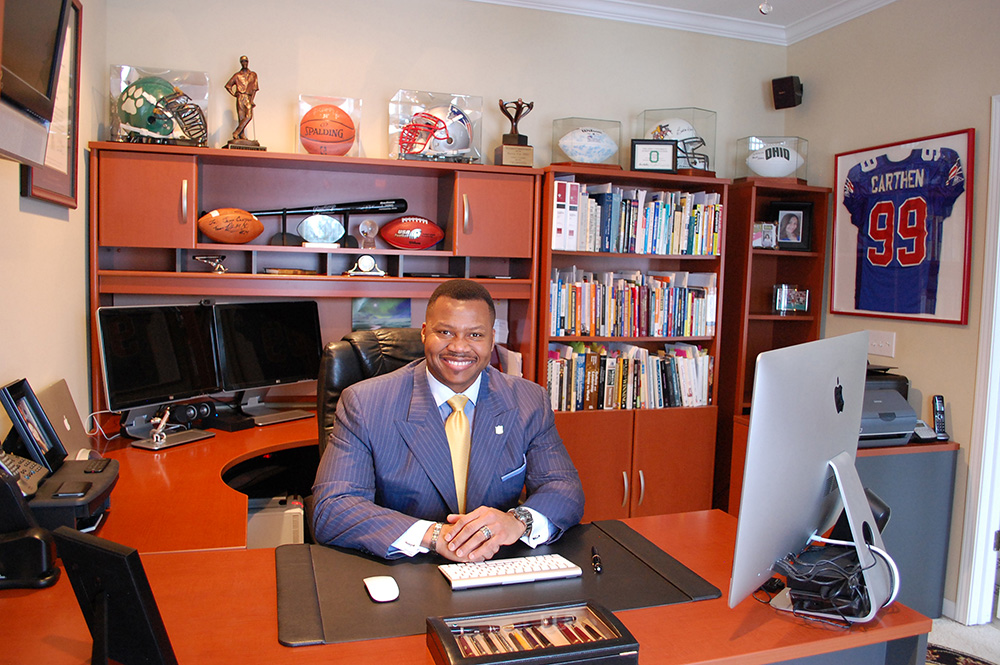 a man in a blue suit sits at a large desk in his office