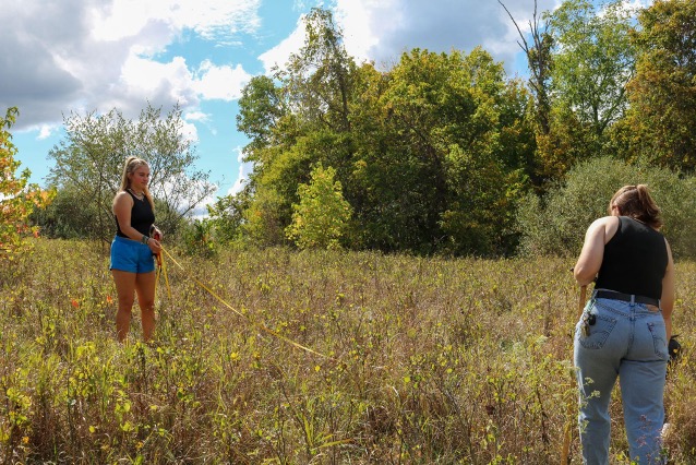 Students measure a space in a grassy field