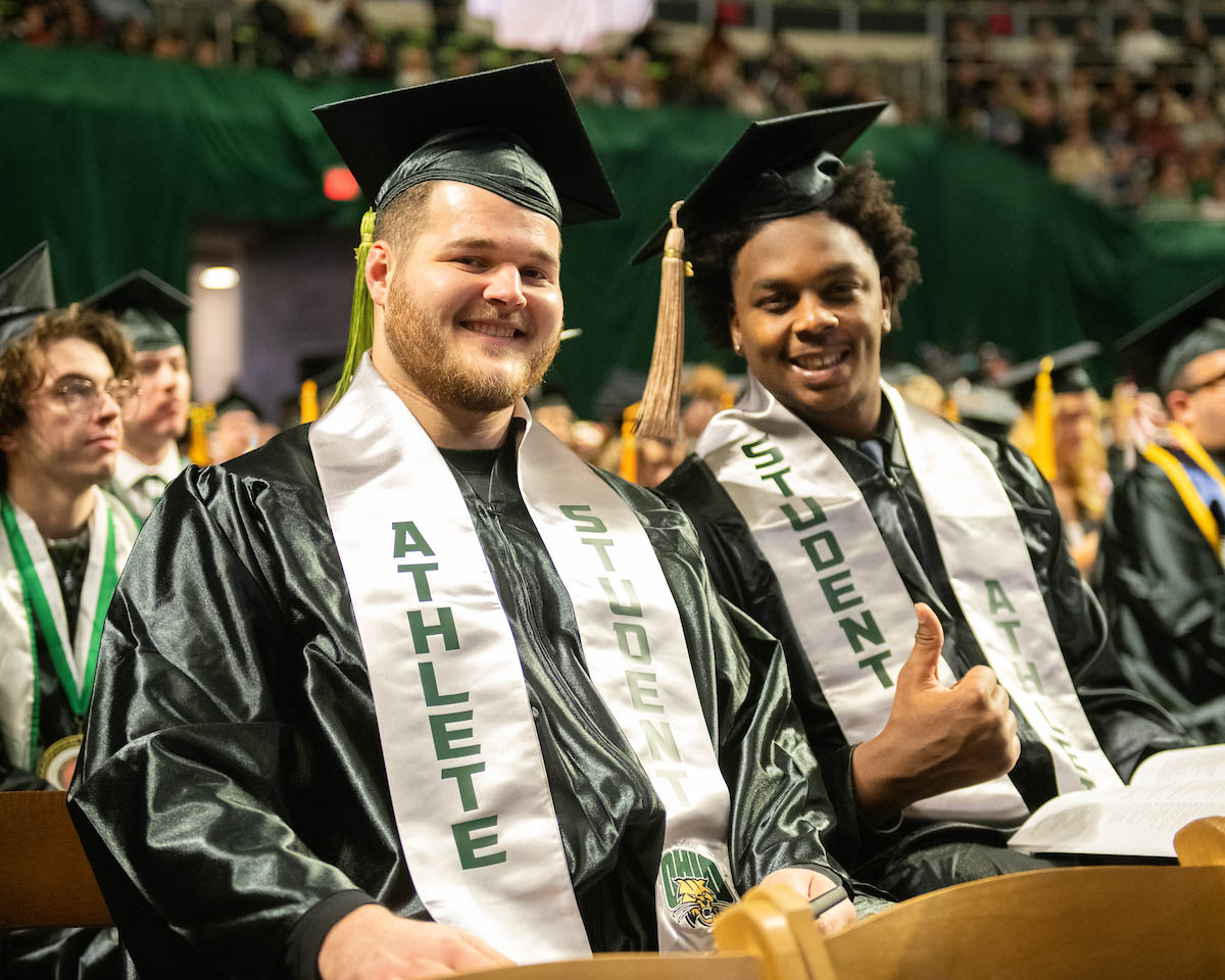 A pair of male graduates display their sashes at commencement