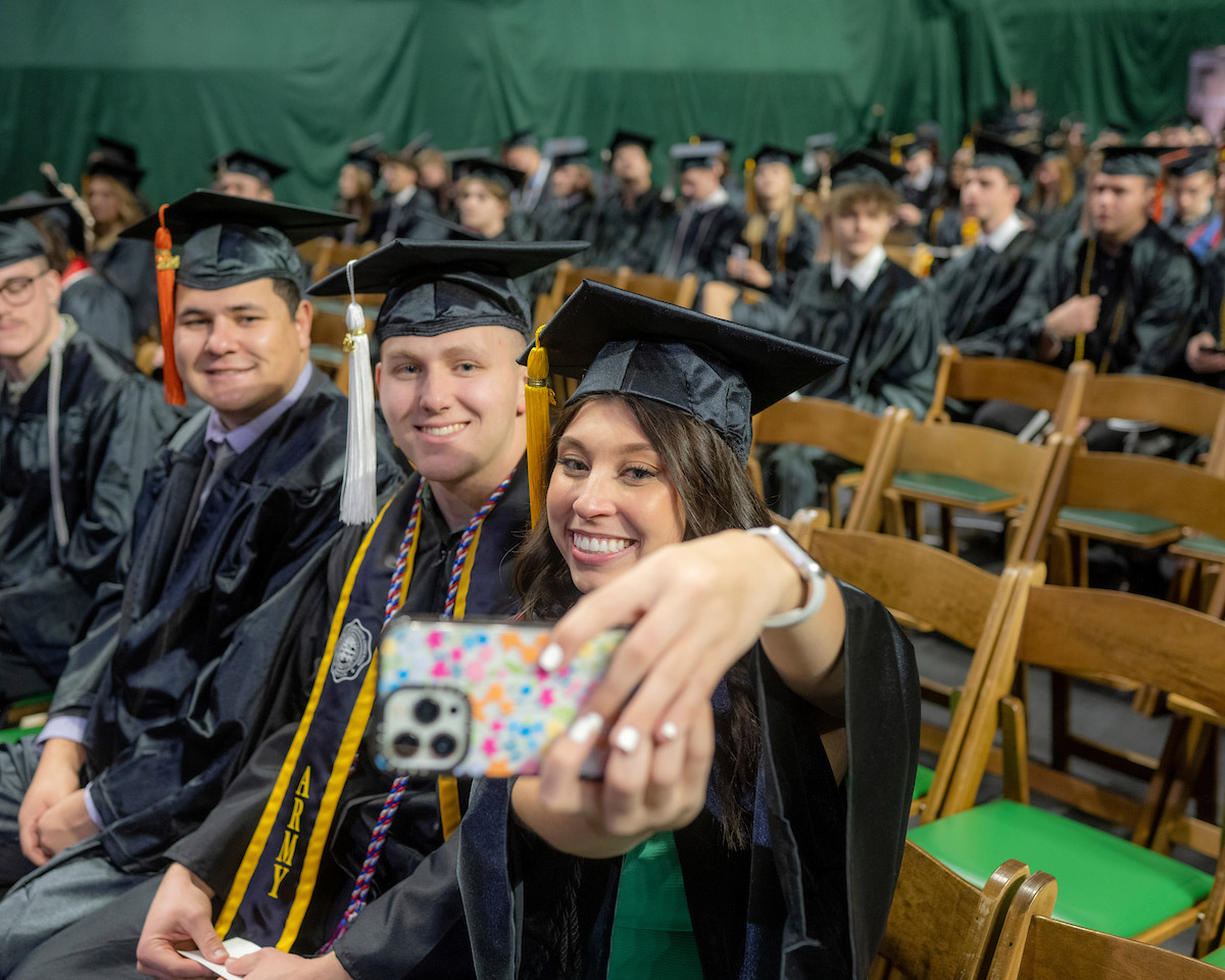 A group of graduates take a selfie at the Fall 2024 commencement ceremony