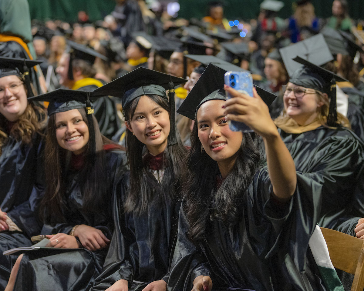 A group of female graduates takes a selfie at commencement