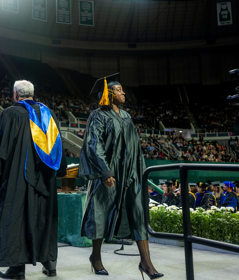 A graduating student walks across the stage at the Fall 2024 commencement ceremony