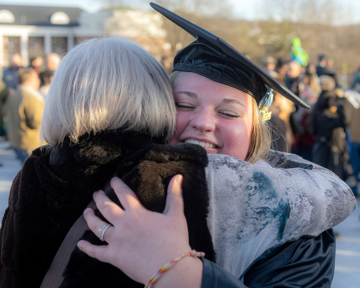 A graduate hugs a supporter following the Fall 2024 commencement ceremony