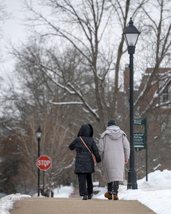 Two individuals  walk hand-in-hand on OHIO's Athens Campus on a snowy day in January