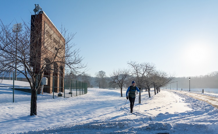 A cross country skier is shown near Peden Stadium and the bike path