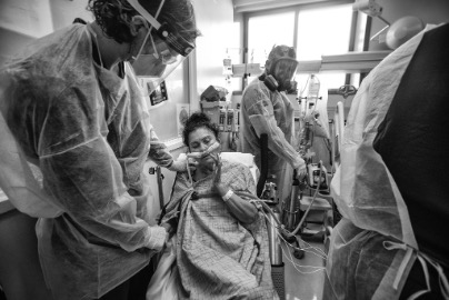 Black and white image of hospital bed with medical professionals tending to a patient