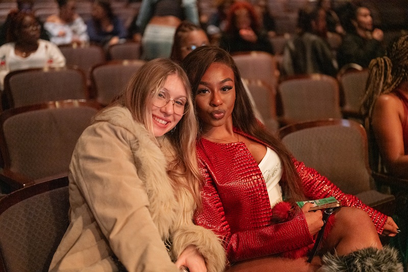 Two audience member smile for a photo at the Mariah The Scientist Concert