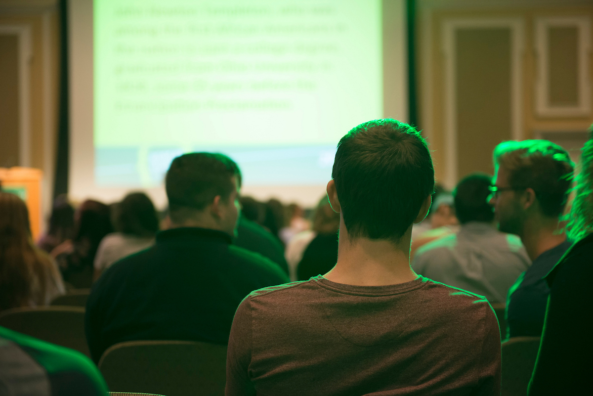 A shot of a conference room with audience members 