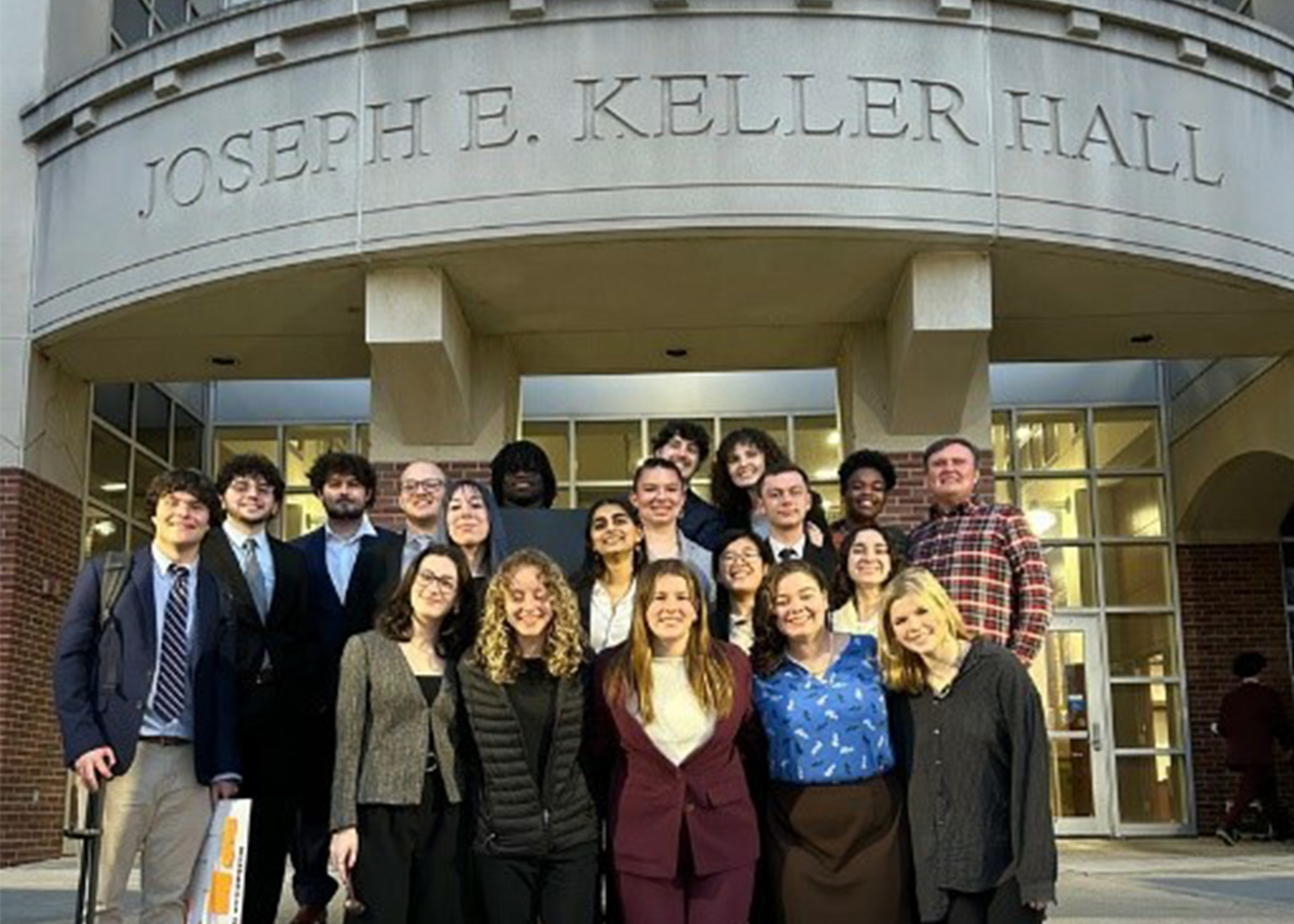 A group of students poses for a picture in front of a law school building