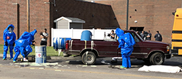 Students in hazardous materials jumpsuits and hoods assess a suspected chemical spill during a critical incident response scenario Friday at the Collins Career Technical Center.