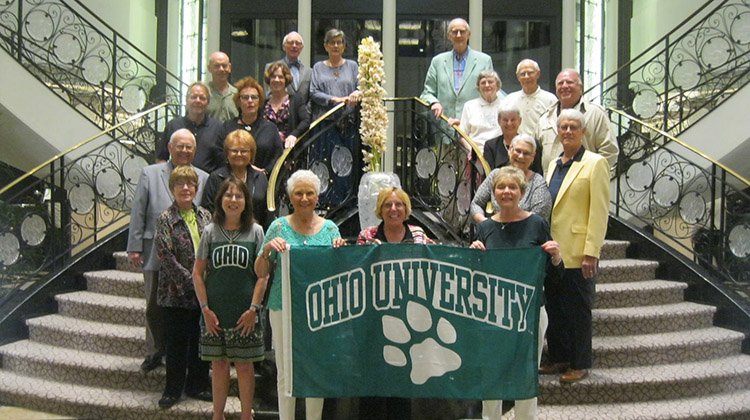 Alumni tour group posing with an OHIO flag on a cruise ship