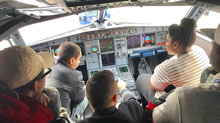 Ohio University aviation alumnus Heath Bowers shows a cockpit to a group of students.