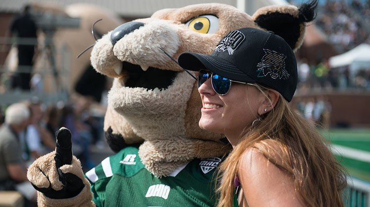 Christine Oblak, an Ohio University College of Business alumna, hugs Rufus during the 2016 Homecoming Football Game. 