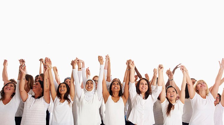 Crowd of diverse women holding hands with arms raised
