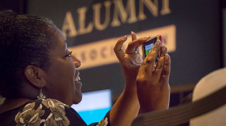 A woman snaps a picture during the Women's Leadership Symposium