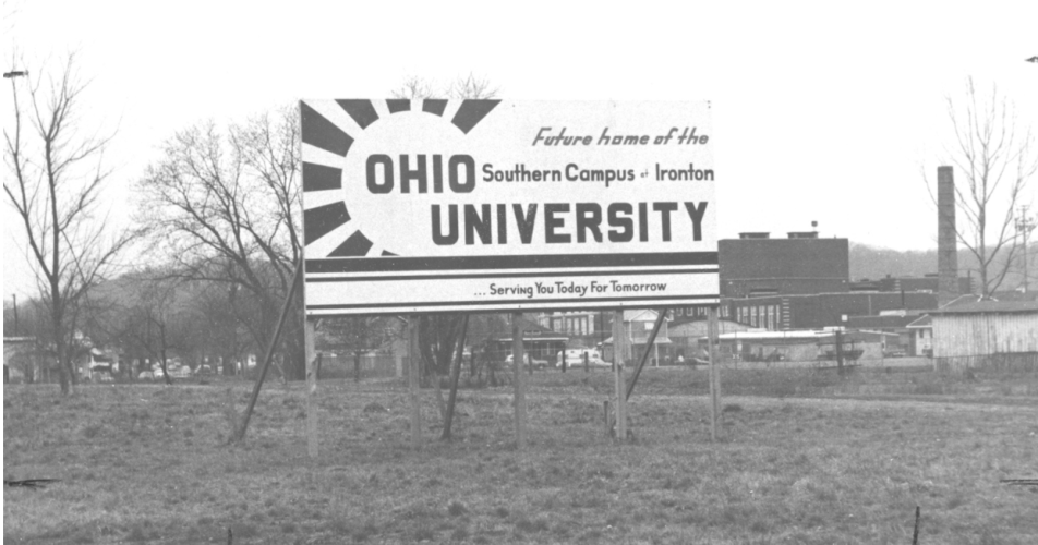 A black and white photo of an old billboard sign that reads "Future home of the Ohio University Southern Campus at Ironton ... Serving You Today For Tomorrow"